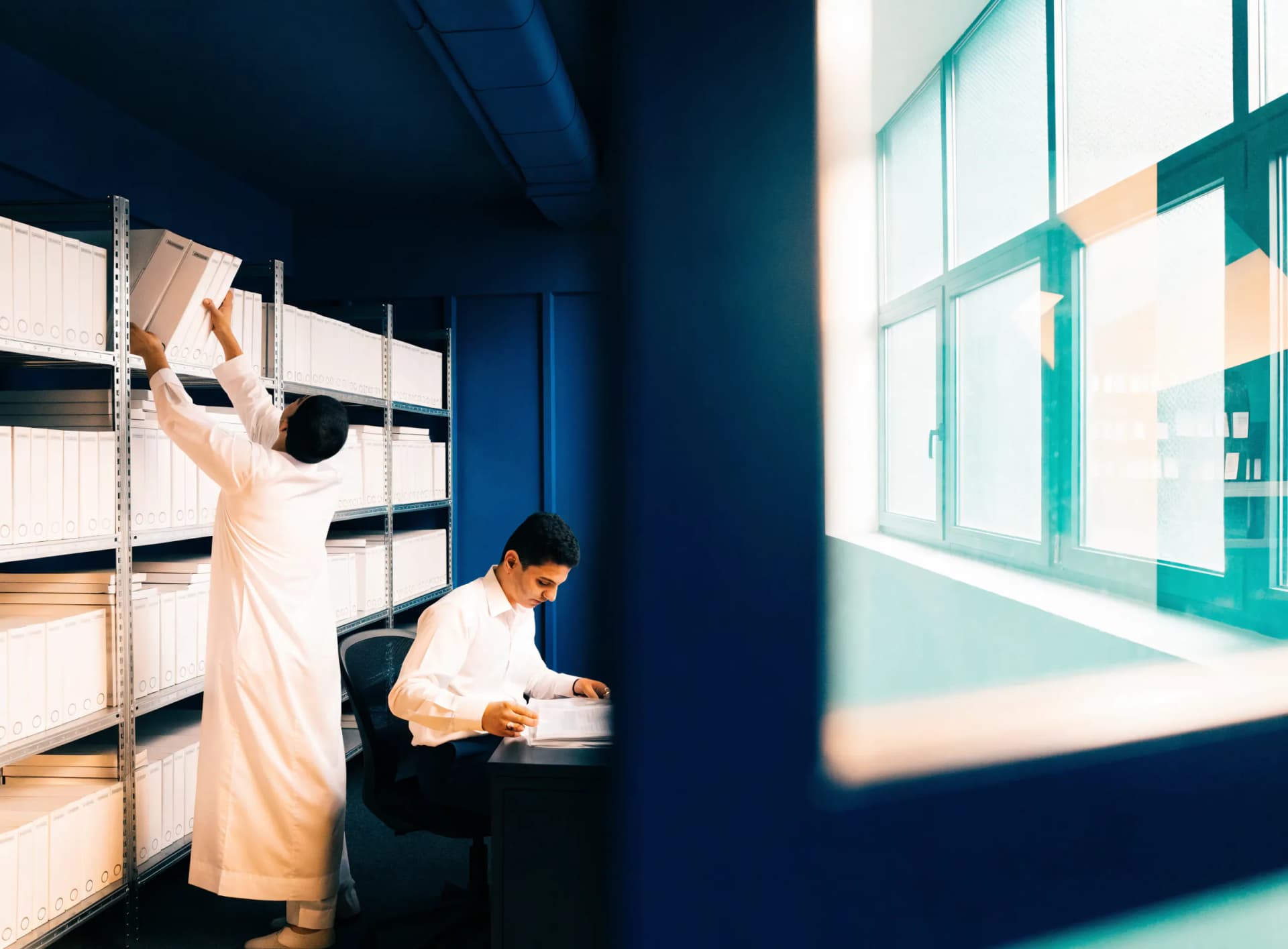 An Emirati records officer shelving stamped policy binders in a Free Zone Authority records room