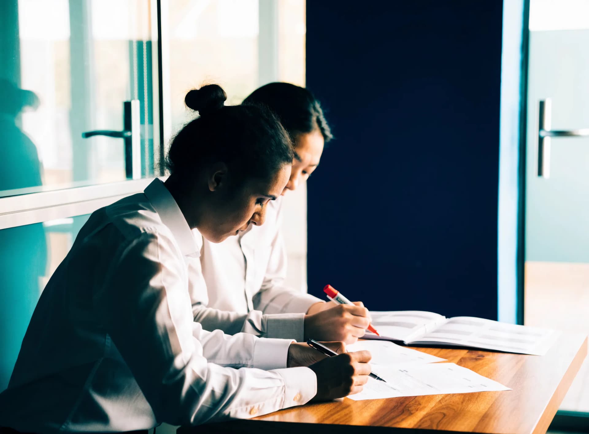Two business-setup consultants comparing printed Free Zone briefing sheets at a low table